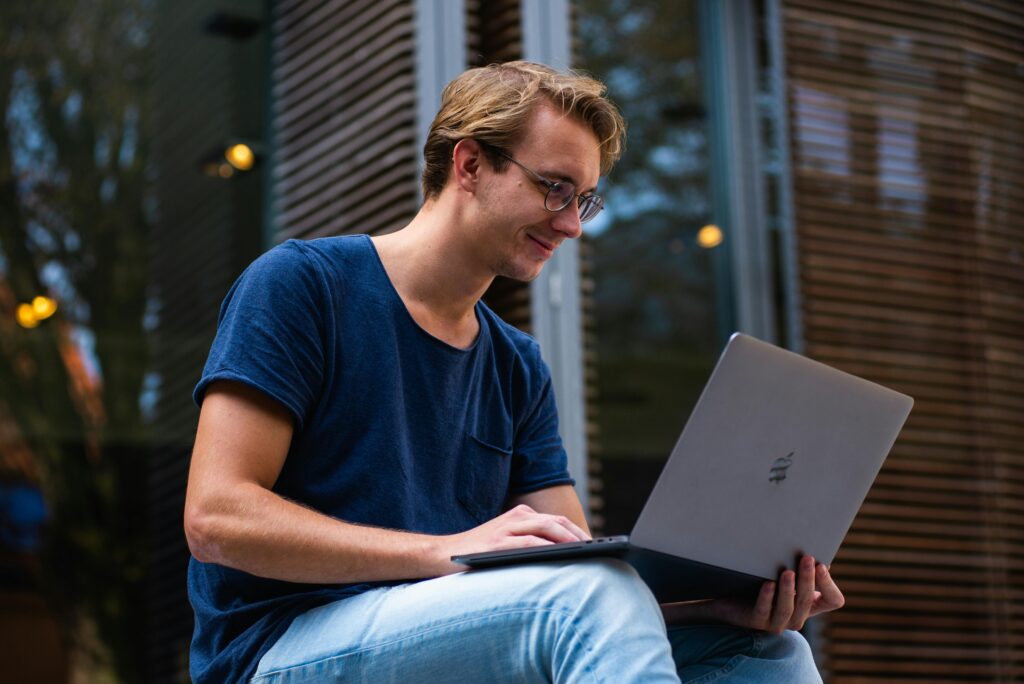 pexels-photo-1438081-1438081 A young man sitting outdoors in Leiden, Netherlands, working on a laptop.